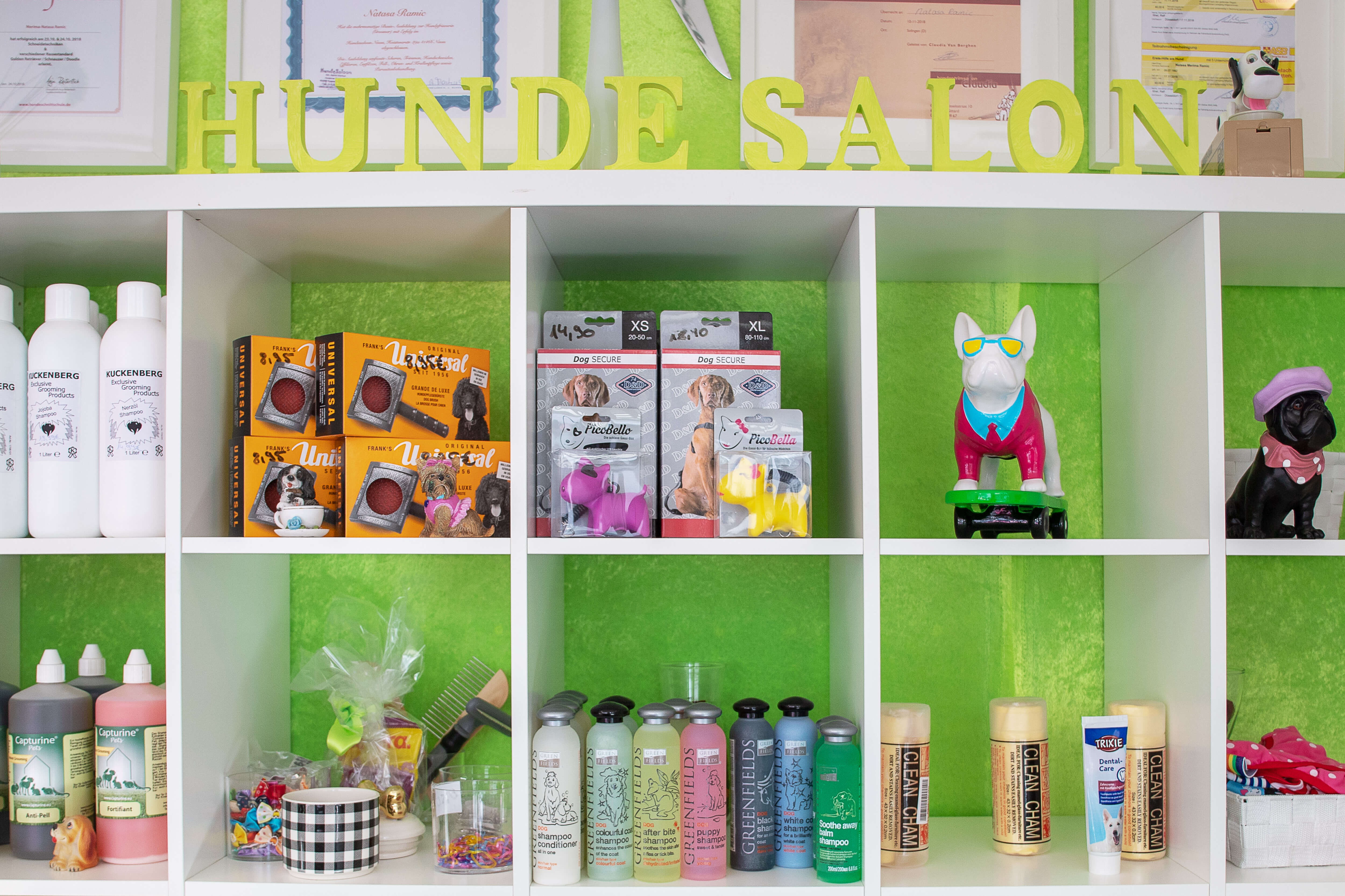 Regal mit verschiedenen Grooming-Produkten im HUNDE SALON, einschließlich Shampoos, Conditioner und Pflegezubehör von Marken wie Natuaa Rano und CLEAN CHAM